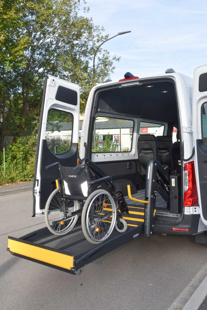 Ausgefahrene Rollstuhlrampe an einem City-Taxi Fahrzeug mit Rollstuhl